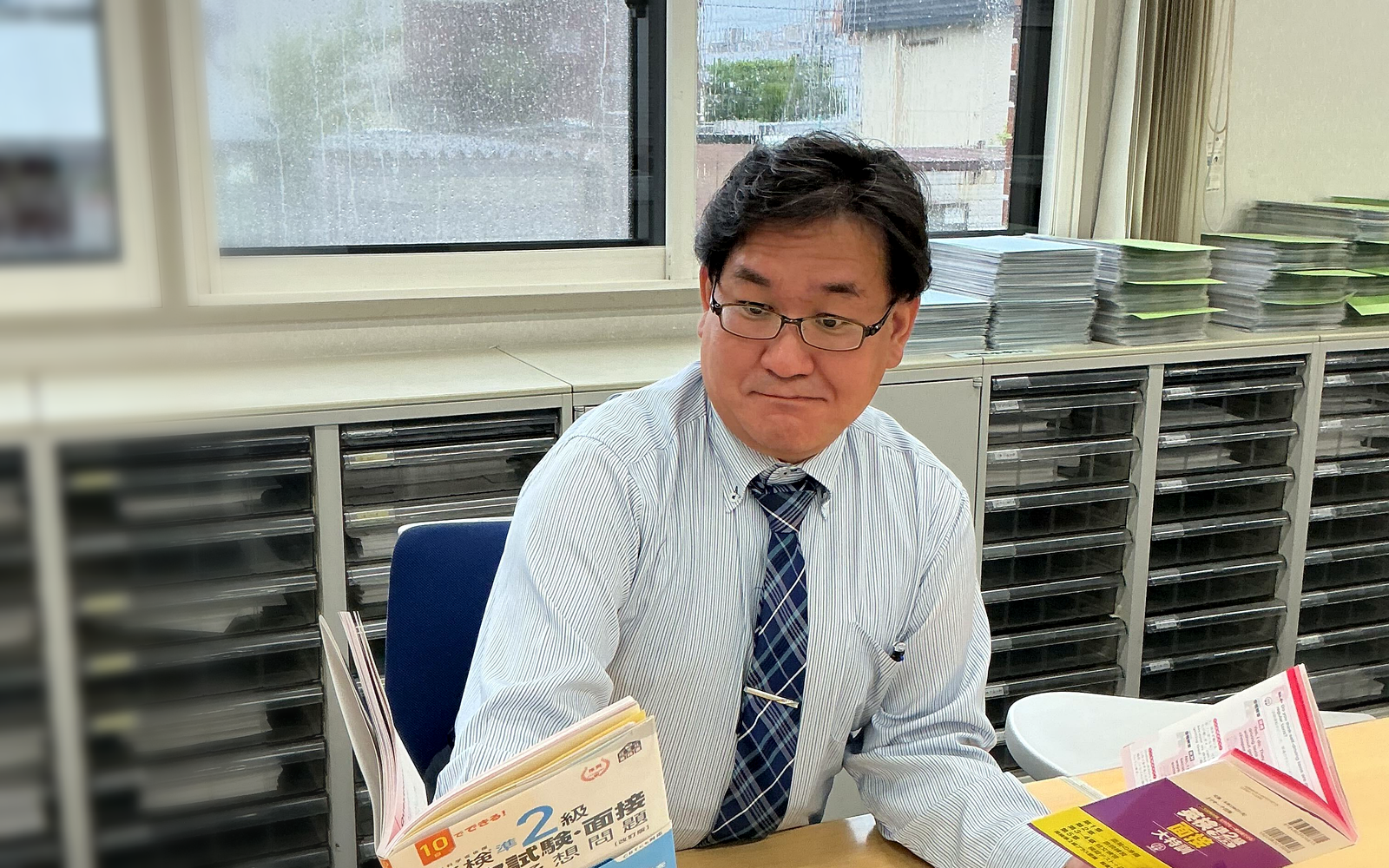 英検®2級の教材を見比べながら学習法を考える木下 学先生