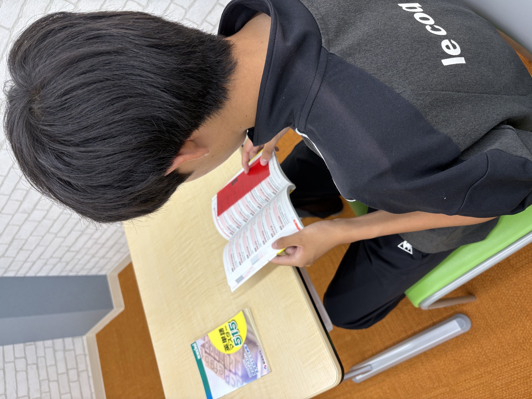 塾生が教室で英単語帳を開いて学習している後ろ姿